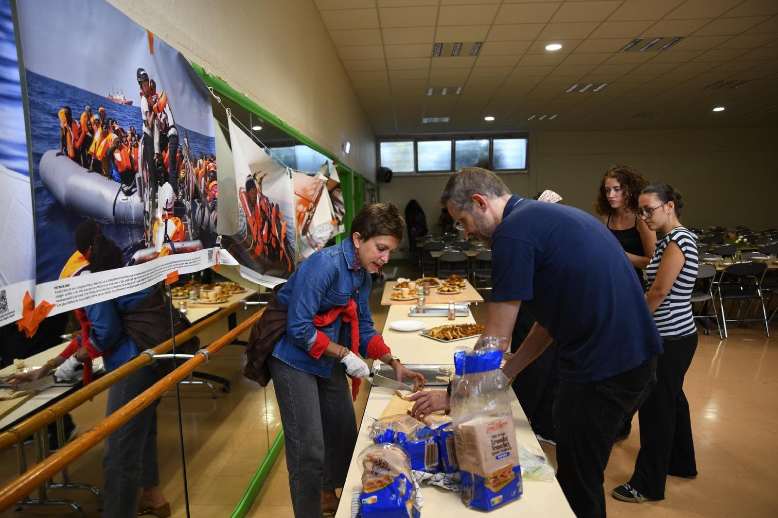 Préparation des sandwichs le long de la table du buffet, sous les photographies de l'exposition