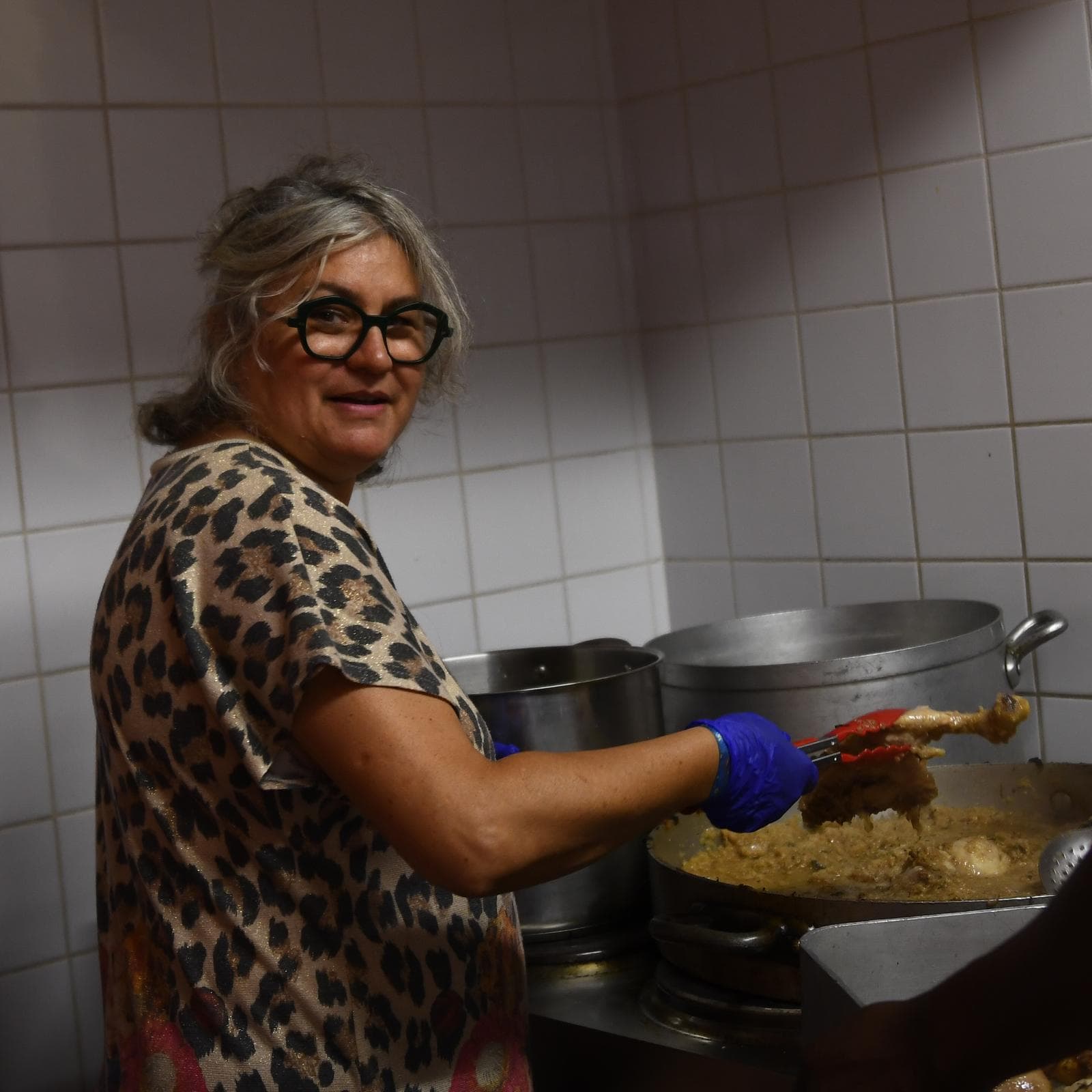 Une bénévole sert le poulet mariné préparé pour le dîner