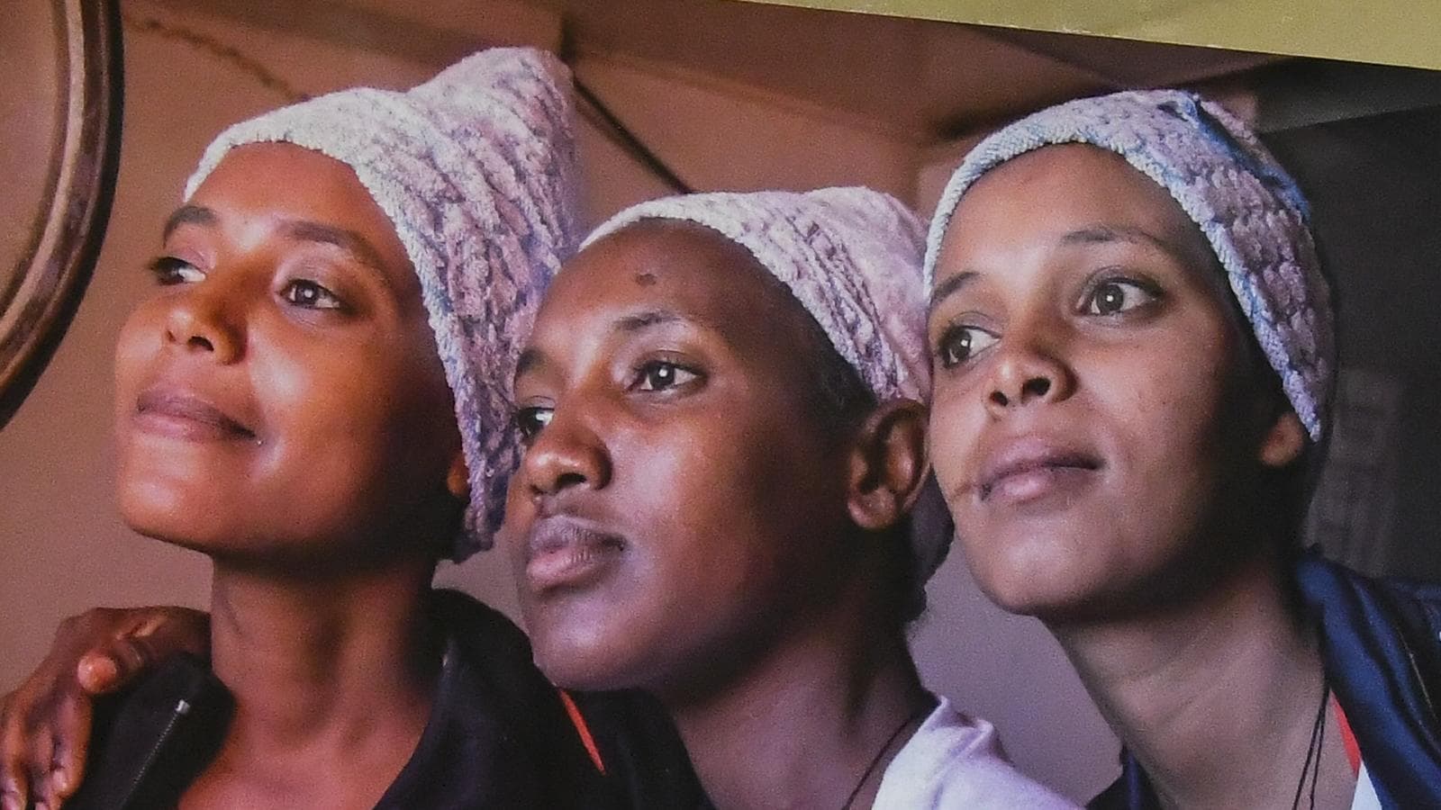 Détail d'une photographie de l'exposition : trois jeunes femmes, le regard tourné vers l'horizon